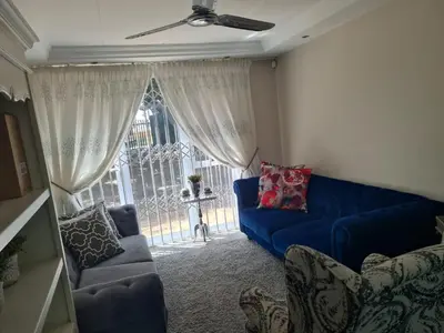 a living room with a blue couch and a window at Villa at 185 Milner Street in Pretoria