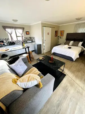 a living room with two beds and a couch at The Shed - Capital Park in Pretoria