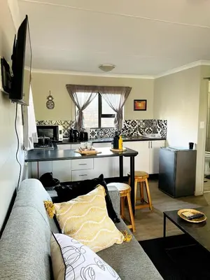 a living room with a couch and a kitchen at The Shed - Capital Park in Pretoria