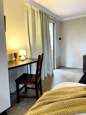a bedroom with a desk and a bed and a bed and a table at The Shed - Capital Park in Pretoria
