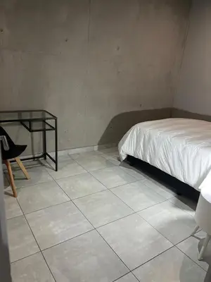 a bedroom with a bed and a chair and a tiled floor at 124 Brooks in Pretoria
