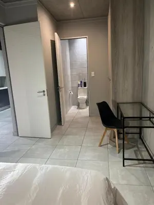 a bedroom with a bed and a glass table and a toilet at 124 Brooks in Pretoria