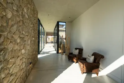 a hallway with chairs and a stone wall at Sajema River Lodge in Hectorspruit