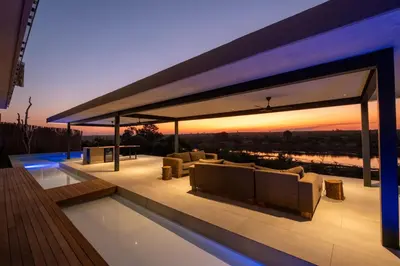 a pavilion with couches and a pool with a sunset at Sajema River Lodge in Hectorspruit