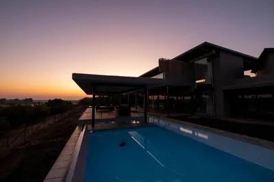 a villa with a swimming pool at sunset at Sajema River Lodge in Hectorspruit