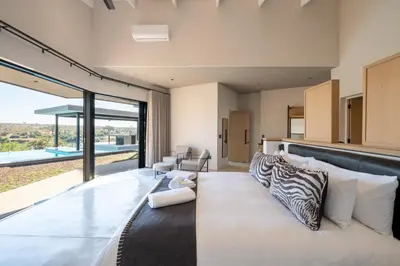 a bedroom with a large bed with a zebra pillows at Sajema River Lodge in Hectorspruit