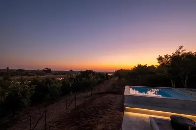 a sunset view of a swimming pool with the sun setting at Sajema River Lodge in Hectorspruit