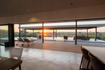 a house with a view of a living room with a table at Sajema River Lodge in Hectorspruit