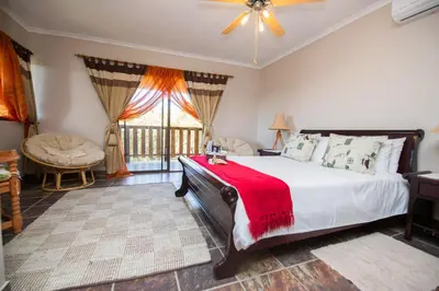 a bedroom with a large bed with a red blanket on it at Foreva Wild in Klipdrift