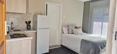 a small kitchen with a bed and a refrigerator at Ekuhlaleni a home away from home R7 in Pretoria