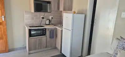 a small kitchen with a white refrigerator and a microwave at Ekuhlaleni a home away from home R7 in Pretoria