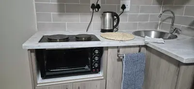 a kitchen counter with a stove and a sink at Ekuhlaleni a home away from home R7 in Pretoria
