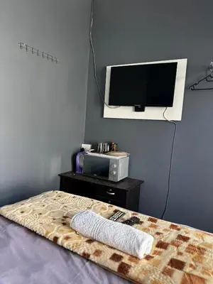 a bedroom with a bed with a tv on the wall at Crown Guesthouse-Waterkloof in Pretoria