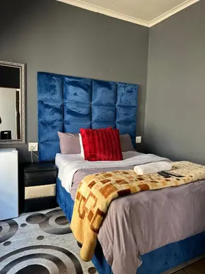 a bedroom with a large bed with a blue headboard at Crown Guesthouse-Waterkloof in Pretoria