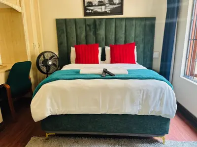 a bedroom with a large bed with red pillows at Crown Guesthouse-Waterkloof in Pretoria