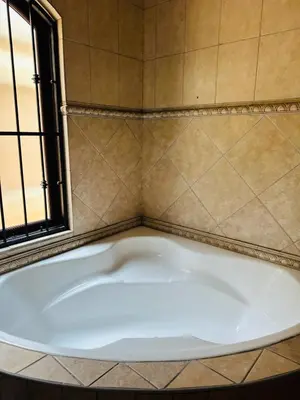 a bath tub in a bathroom with a window at Crown Guesthouse-Waterkloof in Pretoria