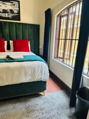 a bedroom with a bed with red pillows and a window at Crown Guesthouse-Waterkloof in Pretoria