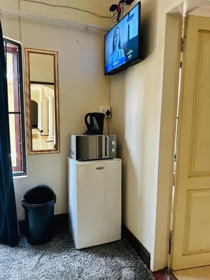 a small refrigerator in a room with a tv on the wall at Crown Guesthouse-Waterkloof in Pretoria