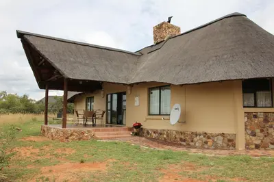 a thatch roofed house with a patio and a table at 205 Zebula 2 bedroom cottage in Warmbaths