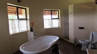 a bathroom with a tub and a toilet and windows at 205 Zebula 2 bedroom cottage in Warmbaths
