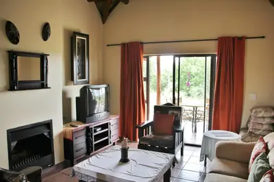 a living room with a couch and a tv at 205 Zebula 2 bedroom cottage in Warmbaths