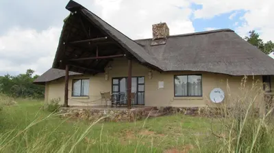 an old house with a thatched roof in a field at 205 Zebula 2 bedroom cottage in Warmbaths