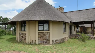 a house with a thatched roof on a field at 205 Zebula 2 bedroom cottage in Warmbaths