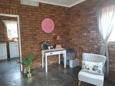 a brick wall with a white desk and a chair at Oppieplaas in Alldays