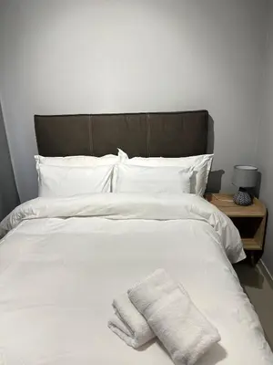 a bed with white sheets and two towels on it at The Olive Nook 2-Bed in Midrand in Midrand
