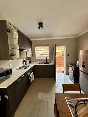 a large kitchen with wooden cabinets and a dining table at The Olive Nook 2-Bed in Midrand in Midrand