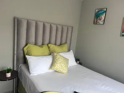 a bed with yellow and white pillows on it at Peaceful Cute Apartment in Pretoria