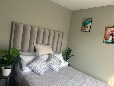 a bedroom with a bed with pillows on it at Peaceful Cute Apartment in Pretoria