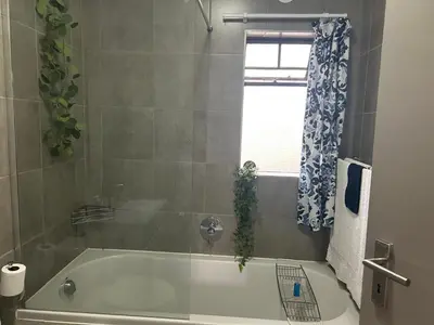 a bathroom with a bath tub and a window at Peaceful Cute Apartment in Pretoria