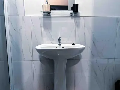 a white sink in a white tiled bathroom at A home away from home cosy luxurious compact 1 bed in Centurion