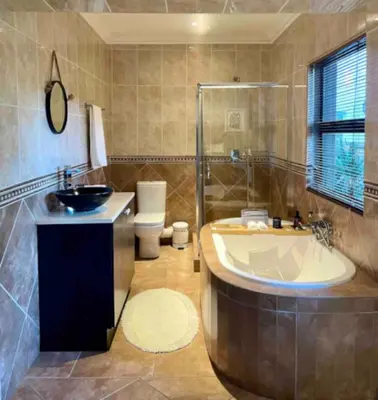a bathroom with a tub and a toilet and a sink at A Private Room with a Private Entrance in Olifantsfontein