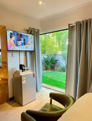 a room with a large window with a television and a chair at A Private Room with a Private Entrance in Olifantsfontein