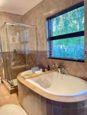 a bathroom with a tub and a glass shower at A Private Room with a Private Entrance in Olifantsfontein