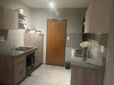 a kitchen with a sink and a vase of flowers on a counter at Gwendolen in Pretoria