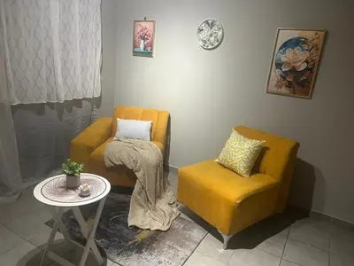 a living room with a yellow chair and a table at Gwendolen in Pretoria