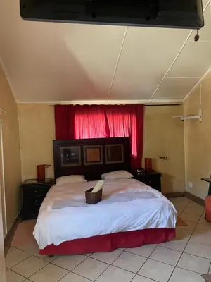 a bedroom with a large bed with a red curtain at Texas Guesthouse in Phalaborwa