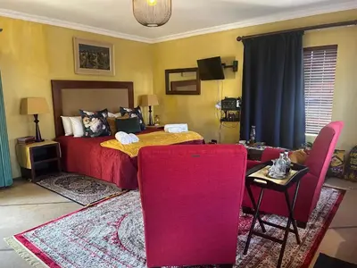 a bedroom with a bed and a table and chairs at Cherry Lane at Cherry Grove in Dullstroom
