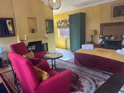 a bedroom with a bed and a couch and chairs at Cherry Lane at Cherry Grove in Dullstroom