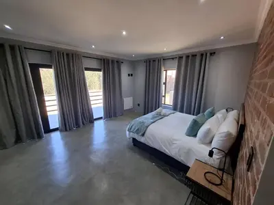 a bedroom with a large bed and windows at The Goose Guesthouse in Dullstroom