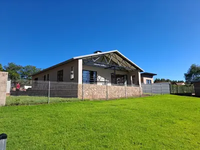 a house with a fence in front of a yard at The Goose Guesthouse in Dullstroom