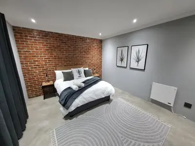 a bedroom with a bed and a brick wall at The Goose Guesthouse in Dullstroom