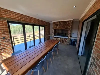 a large wooden table and chairs in a room with a fireplace at The Goose Guesthouse in Dullstroom