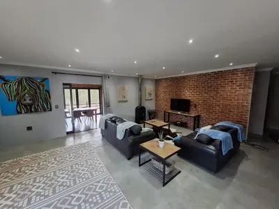 a living room with two couches and a brick wall at The Goose Guesthouse in Dullstroom