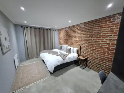 a bedroom with a brick wall and a bed at The Goose Guesthouse in Dullstroom