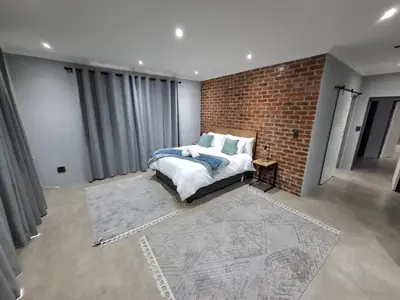 a bedroom with a bed and a brick wall at The Goose Guesthouse in Dullstroom