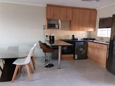 a kitchen with wooden cabinets and a table and chairs at Lovely 2 Bedroom Townhouse with private garden in Centurion
